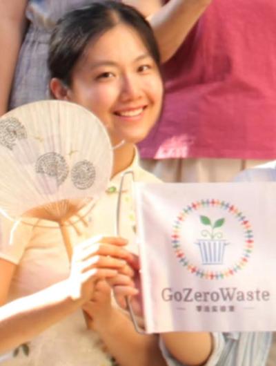Headshot of Leilani Danning with a Go Zero Waste flag. 