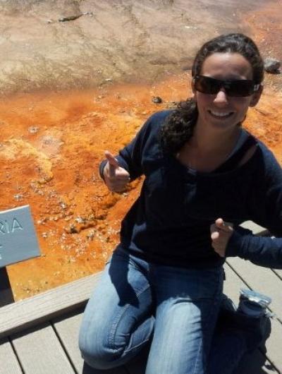 Photo of Lauren Brooks next to a sign labeled "Bacteria Mat: