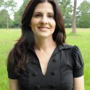 Headshot of Kelli Ondracek in black blouse with grasses and trees in the background