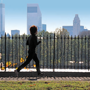 Child running on grass with city skyline in the background