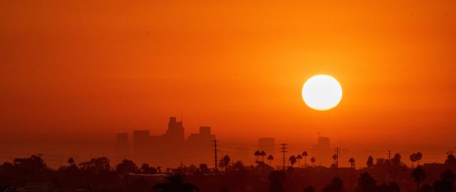 Sun sets over a city during a heat wave, with a red sky