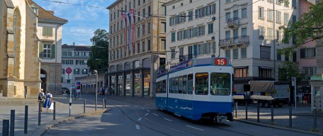 tram car in Zurich with pedestrians, buildings, and greenery
