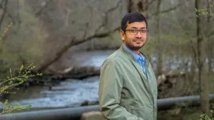 Lav Kanoi in a dark green jacket standing in front of a river