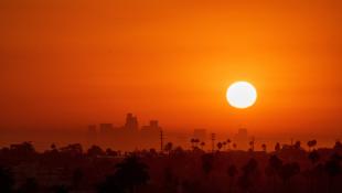 Sun sets over a city during a heat wave, with a red sky