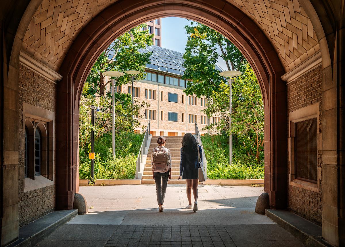 two students walking through arch on YSE campus