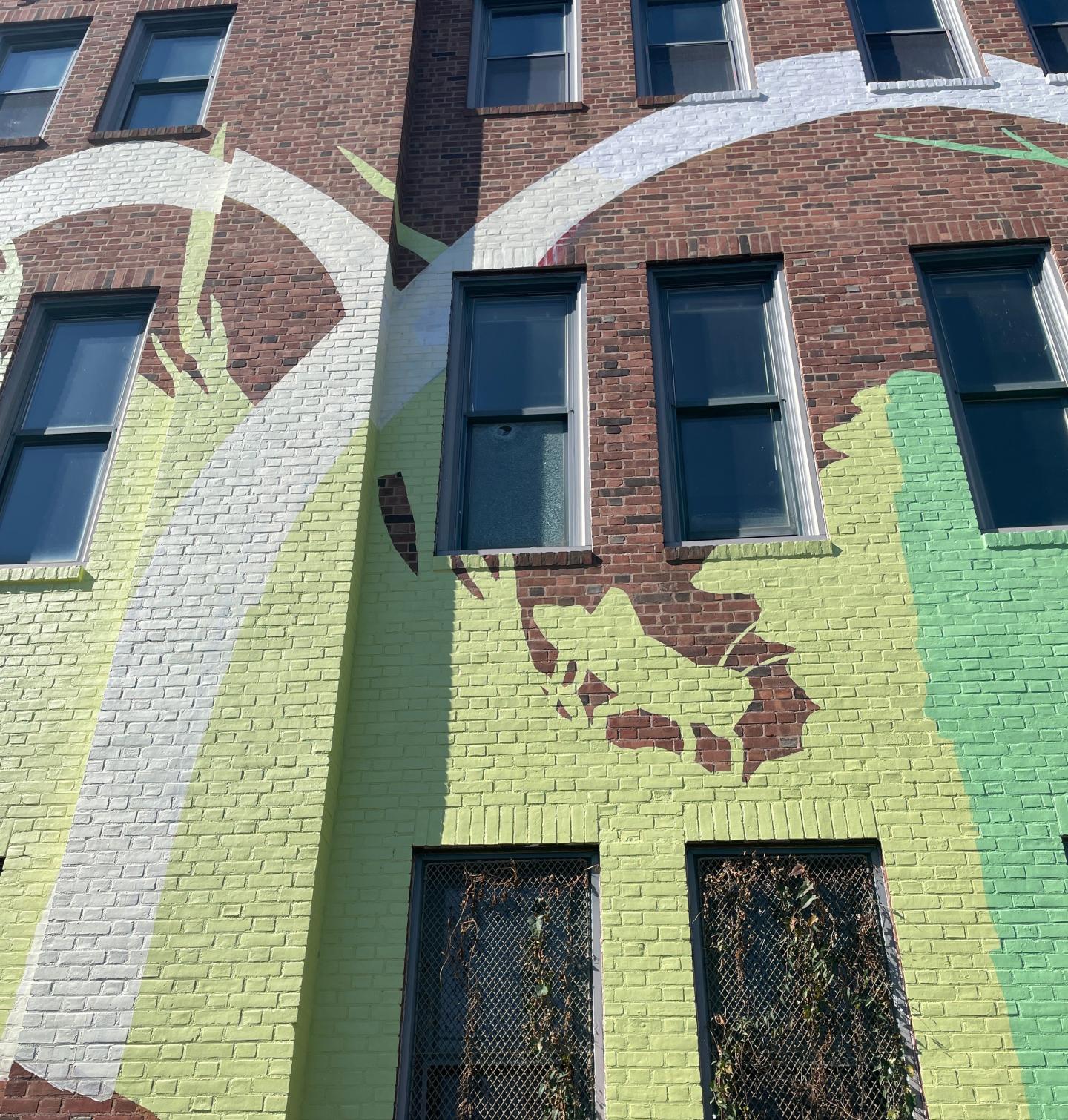 brightly colored mural with grasshopper on the side of a two-story building