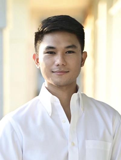 headshot of Mars Arriesgado in a white shirt against a tan background