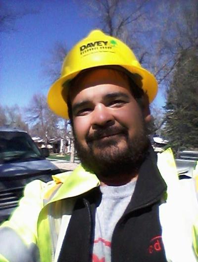 Adrian Camancho in proper tree planting clothing, including a hard hat and reflective jacket.