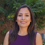 Headshot of Somayeh Dodge in a purple blouse with foliage in the background