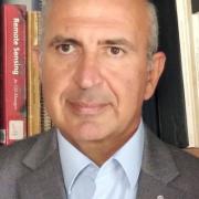 headshot of Nektarios Chrysoulakis in gray blazer with books in background