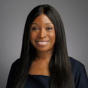 Headshot of Manja Kargbo in a black blouse against a dark gray background