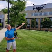 Mike Alonzo in a blue shirt pointing to an airborne drone