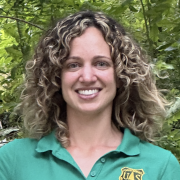 Headshot of Nancy Sonti in a green shirt with foliage in the background