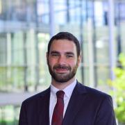 Headshot of Benjamin Cohen with glass building in background