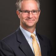 Headshot of Michael Crair in a dark suit against black background