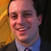 Headshot of Grant Ervin in suit against black and yellow background