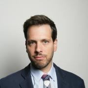 Headshot of Scott Rosenstein in dark suit against gray background